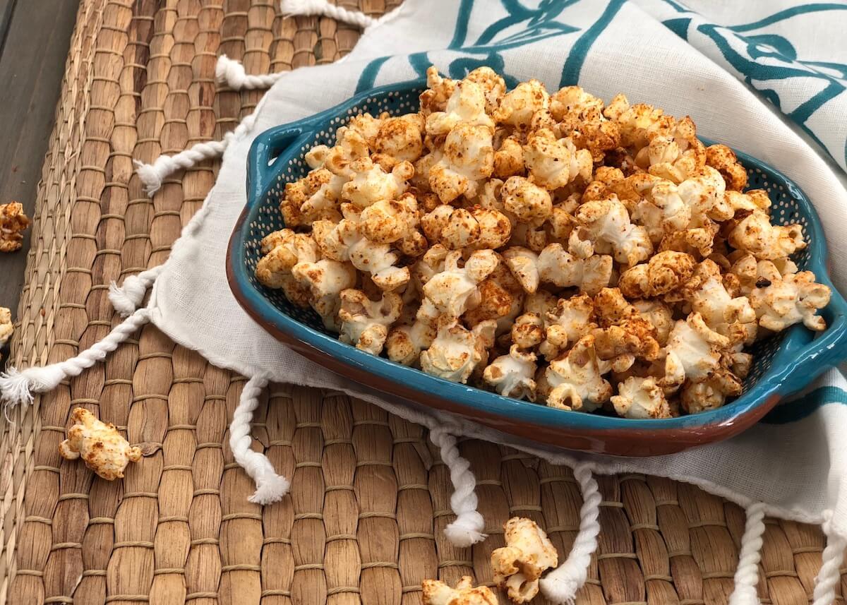 Sweet Chili Spiced Popcorn in blue bowl on brown woven placemat