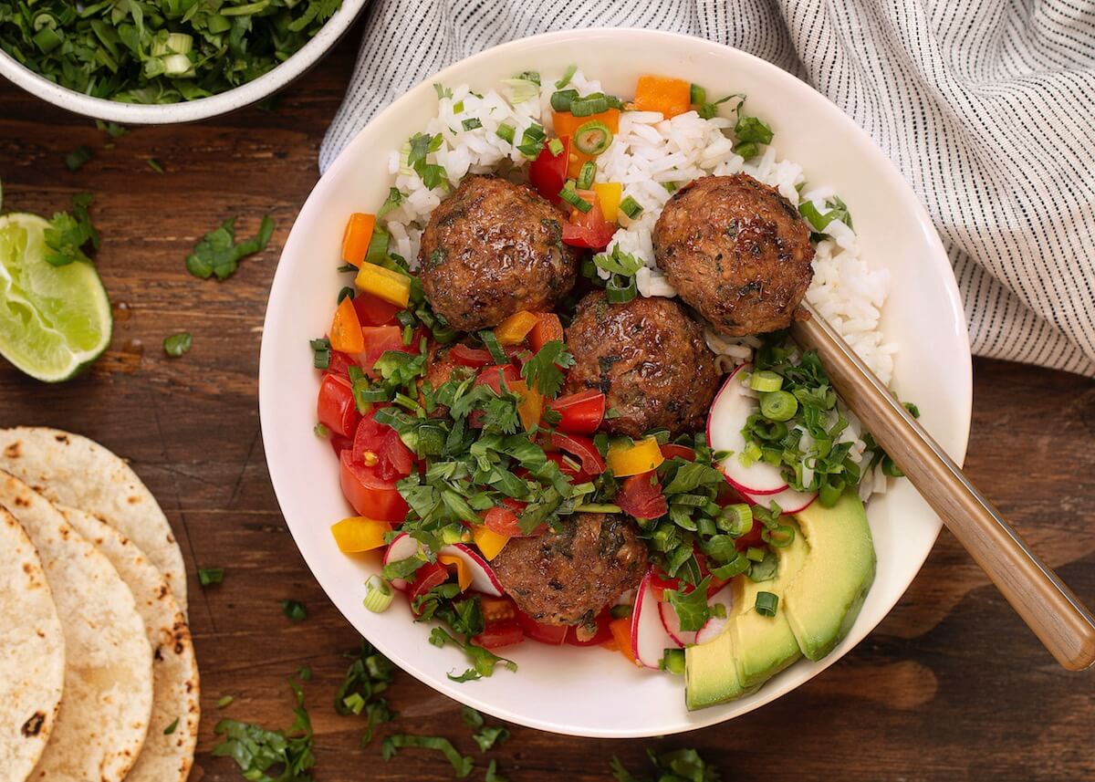 Chipotle Chicken Meatballs over white rice in bowl with spoon