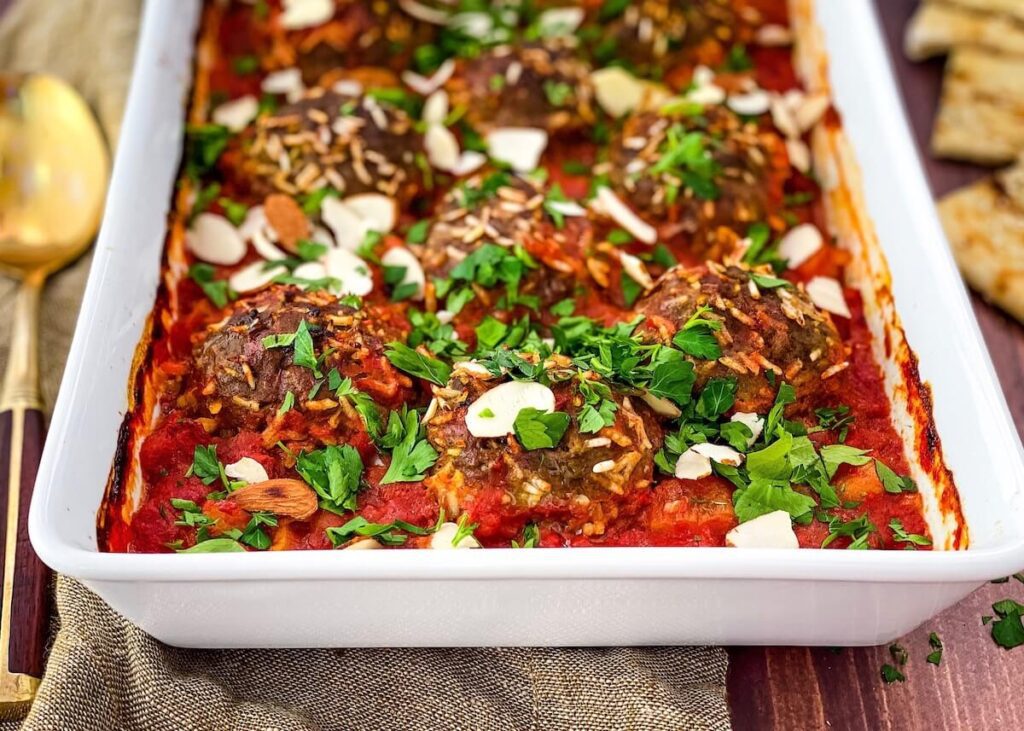 porcupine meatballs in white baking dish with parsley