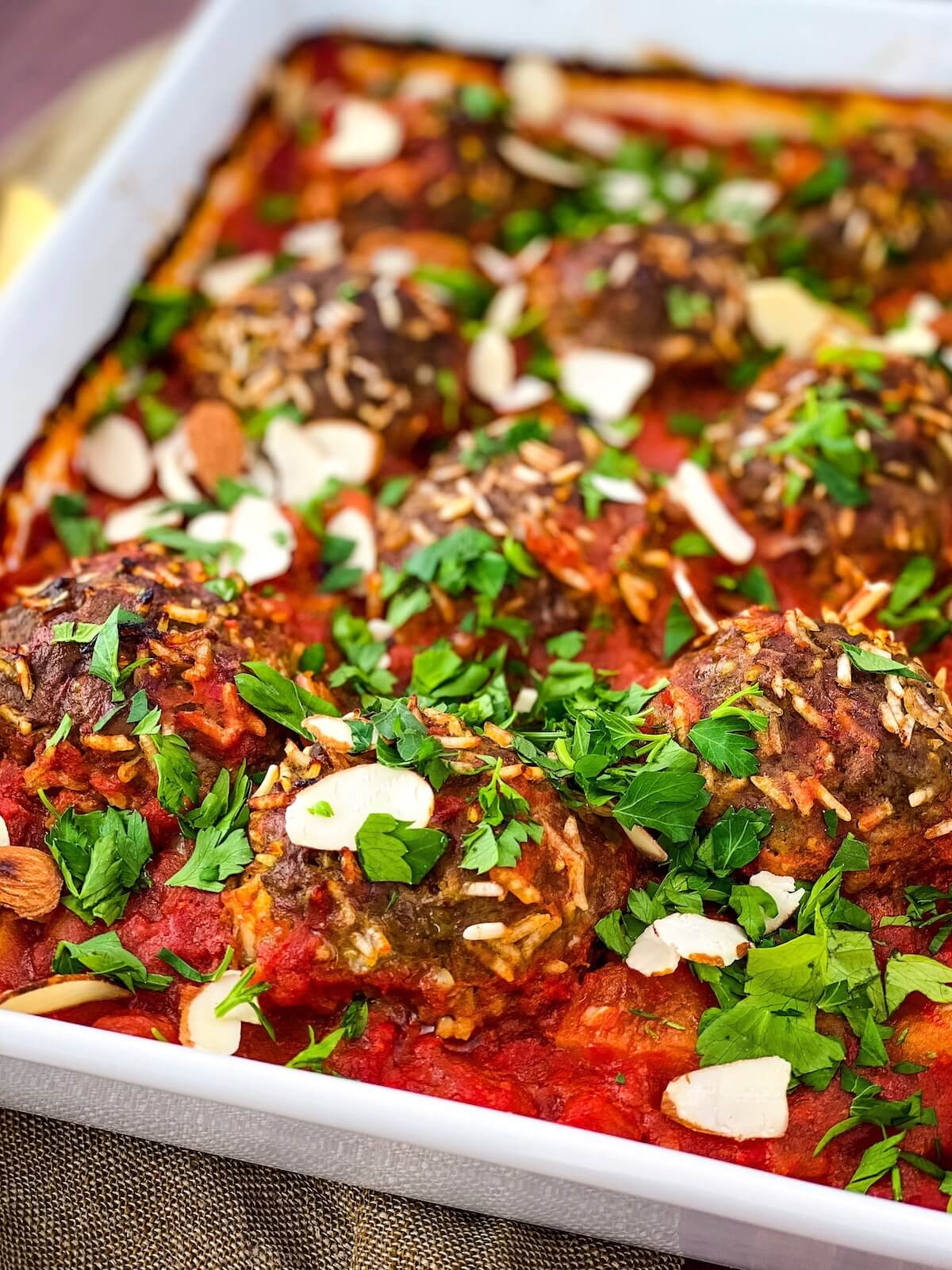 meatballs with parsley and almonds on top in a dish