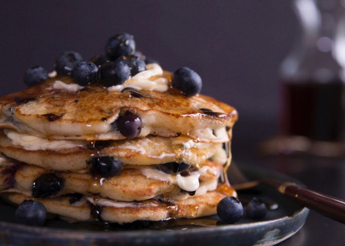 stack of blueberry pancakes with butter and syrup