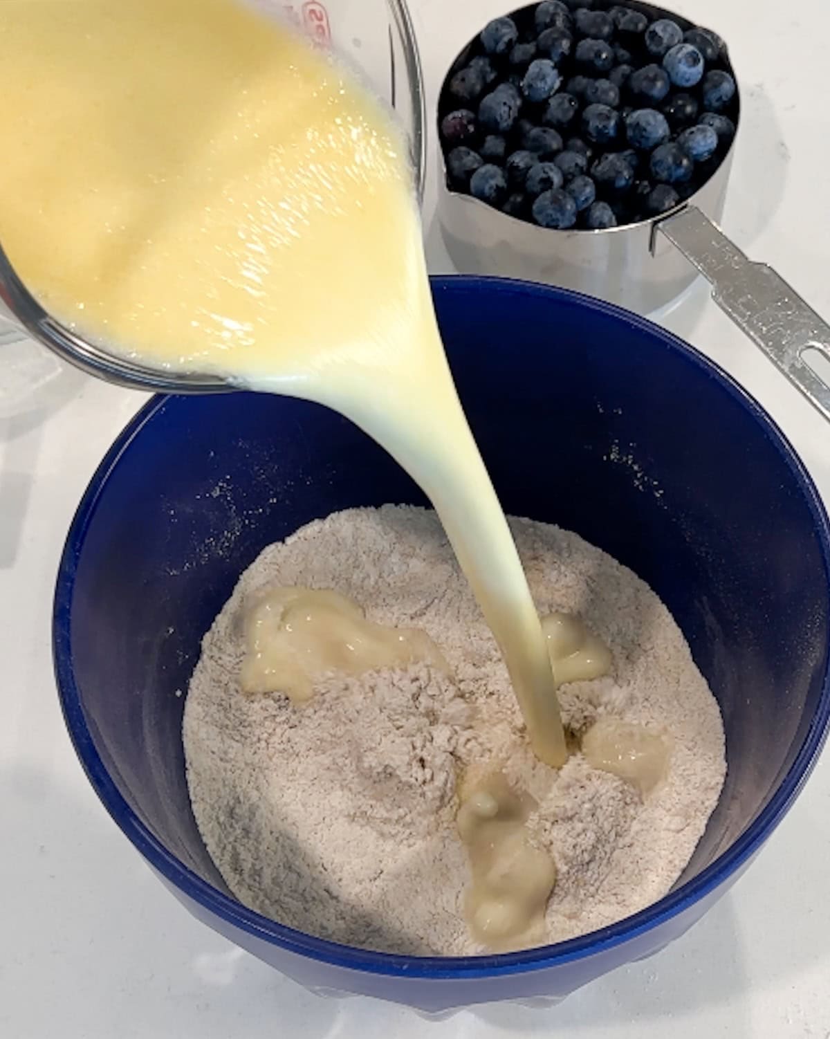 Adding wet ingredients to dry ingredients for pancake batter.