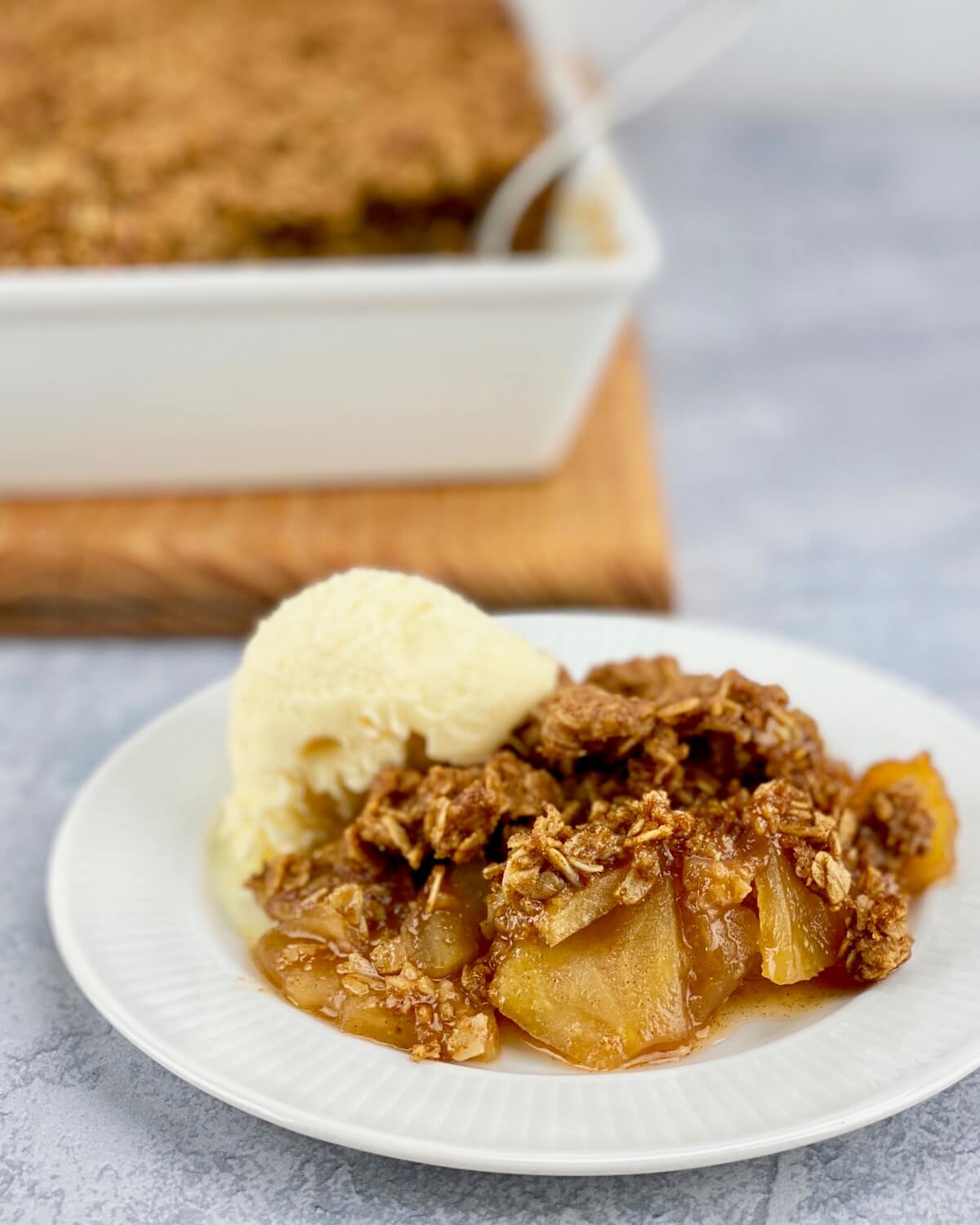 apple crisp with oats on small white plate with ice cream