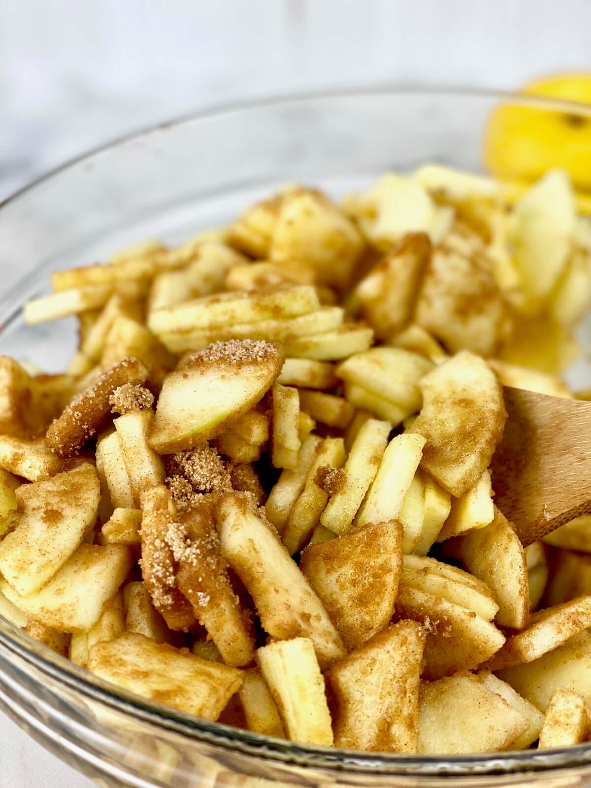 slice apples with brown sugar and cinnamon in medium-size glass bowl