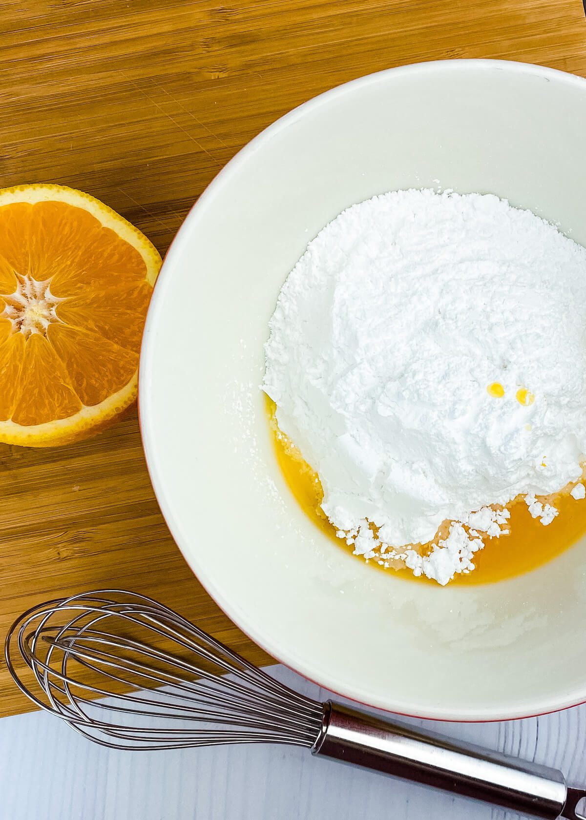 bowl with sugar and orange juice with whisk