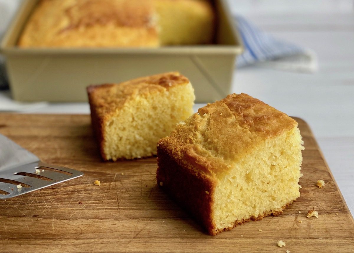 tall slice of yellow cornbread on a cutting board