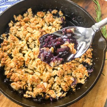 blueberry crisp in a skillet with a spoonful taken out