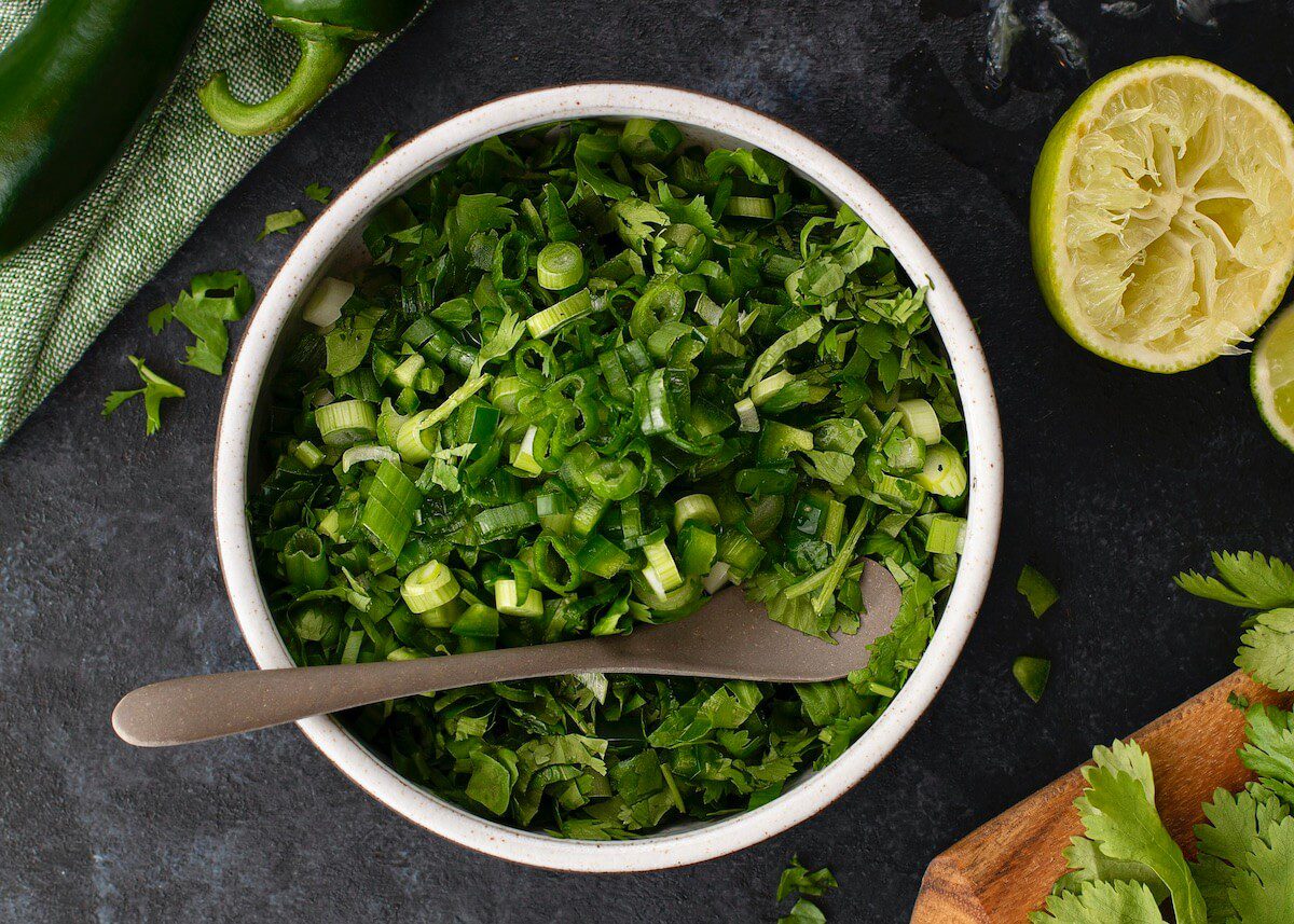 Cilantro salsa in bowl with spoon on black surface