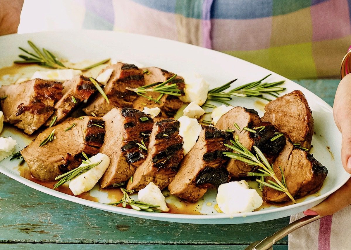 grilled pork tenderloin on oval white platter with rosemary