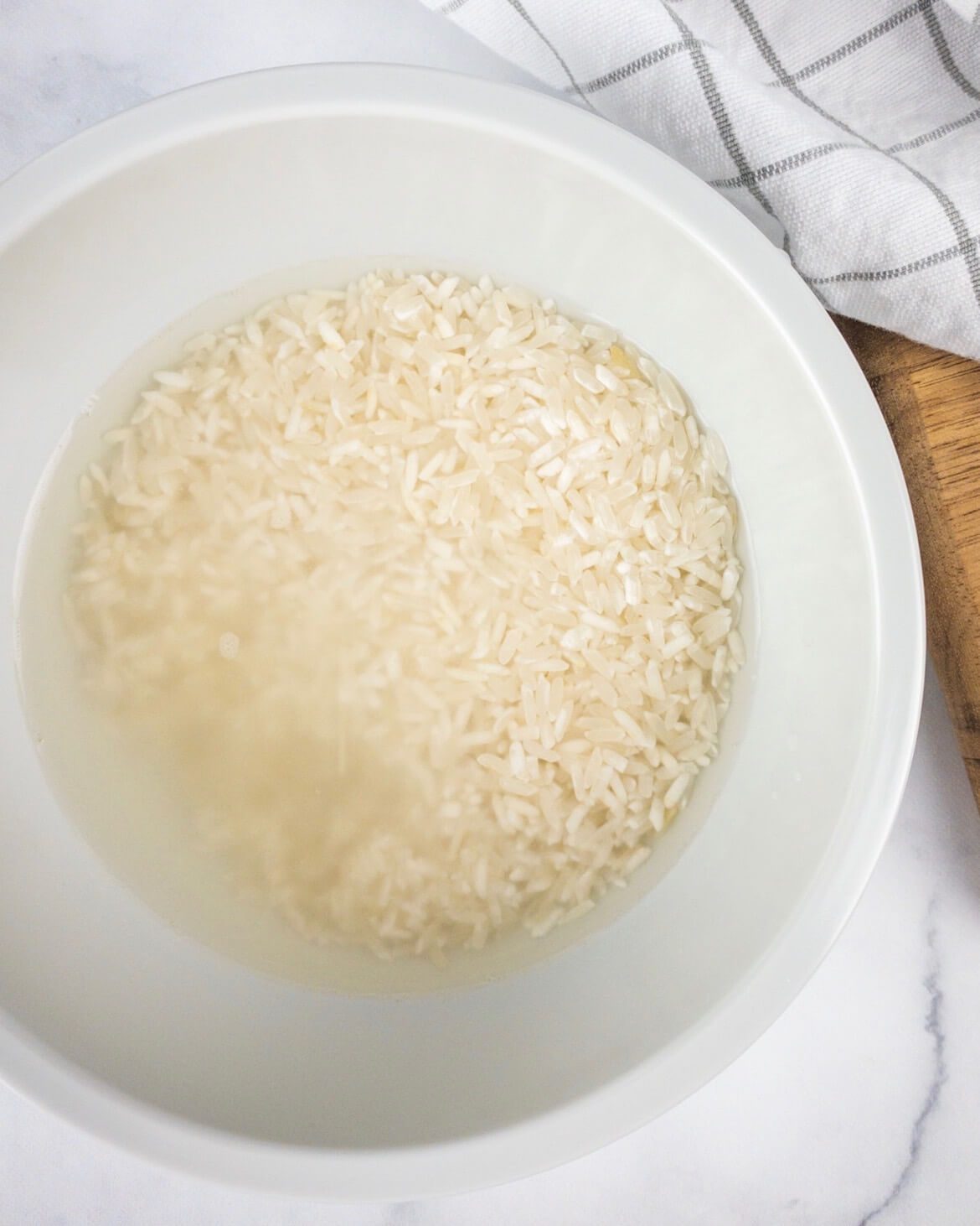 rice soaking in water in a bowl on marble surface