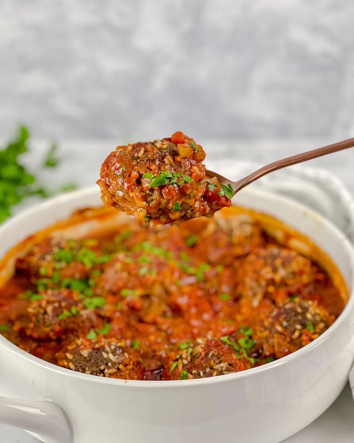 spoon with beef meatball on it with tomato sauce