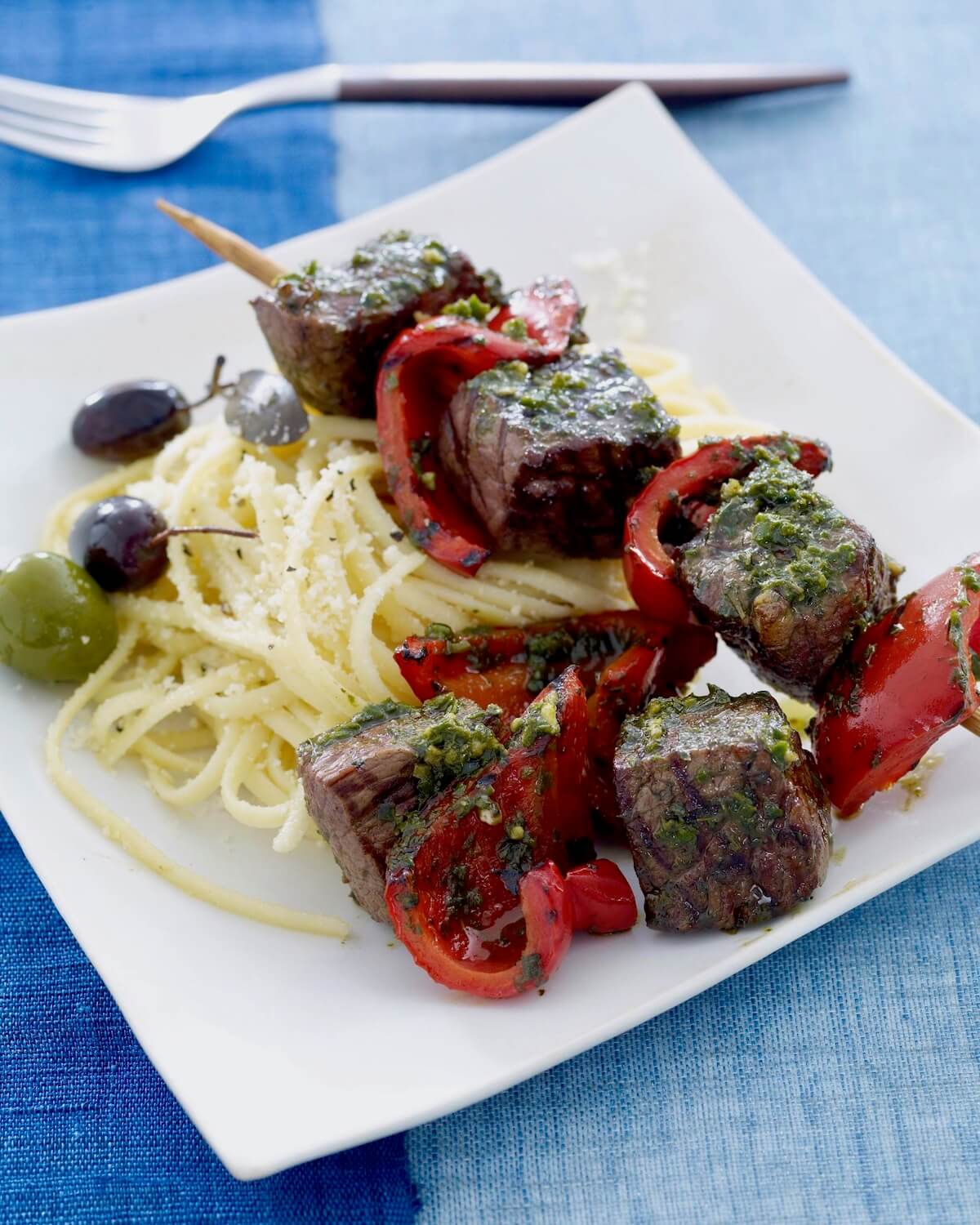 grill steak kabobs with pesto on white plate with pasta