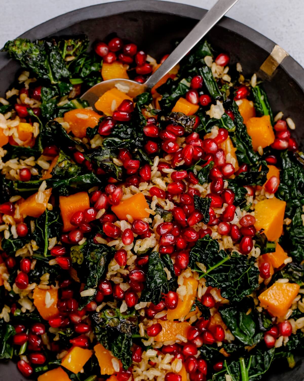 kale and squash salad with brown rice with pomegranates as garnish