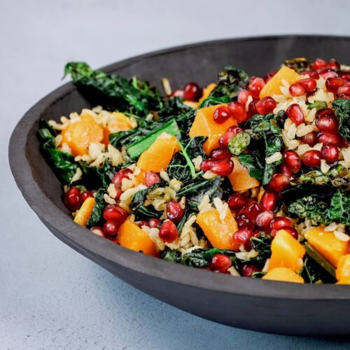 kale and squash salad with brown rice and pomegranates in a slate bowl feature