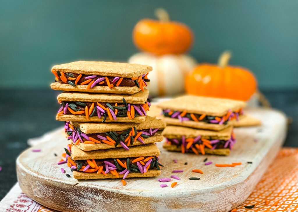 stack of graham crackers filled with chocolate frosting and purple and orange sprinkles