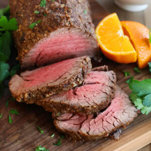 Close up of slices of beef tenderloin on a cutting board.