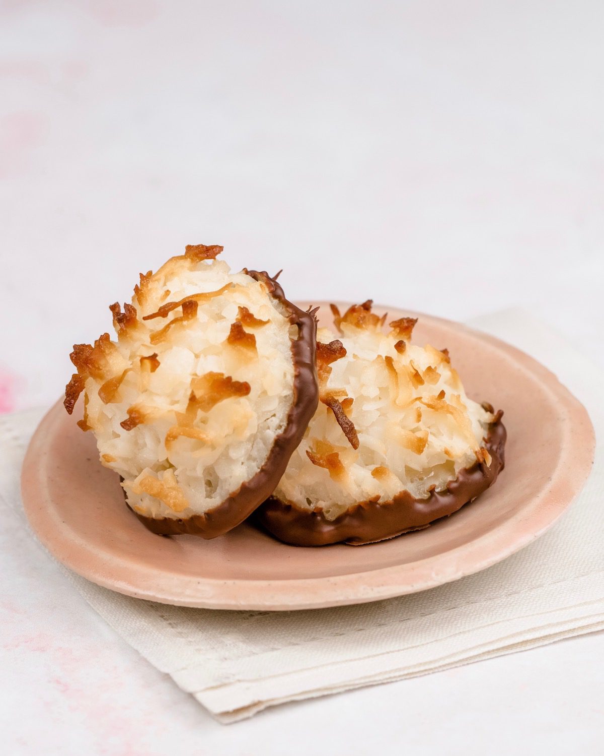 coconut macaroon cookies dipped in chocolate on pink plate