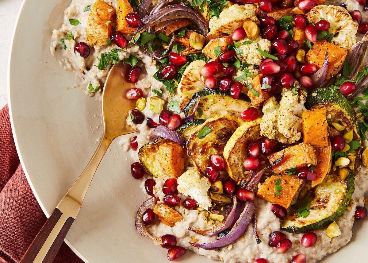 roasted eggplant dip with vegetables and pomegranates in a white bowl