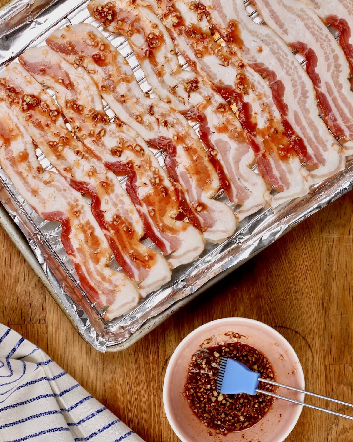 brushing maple sauce on raw bacon for the oven