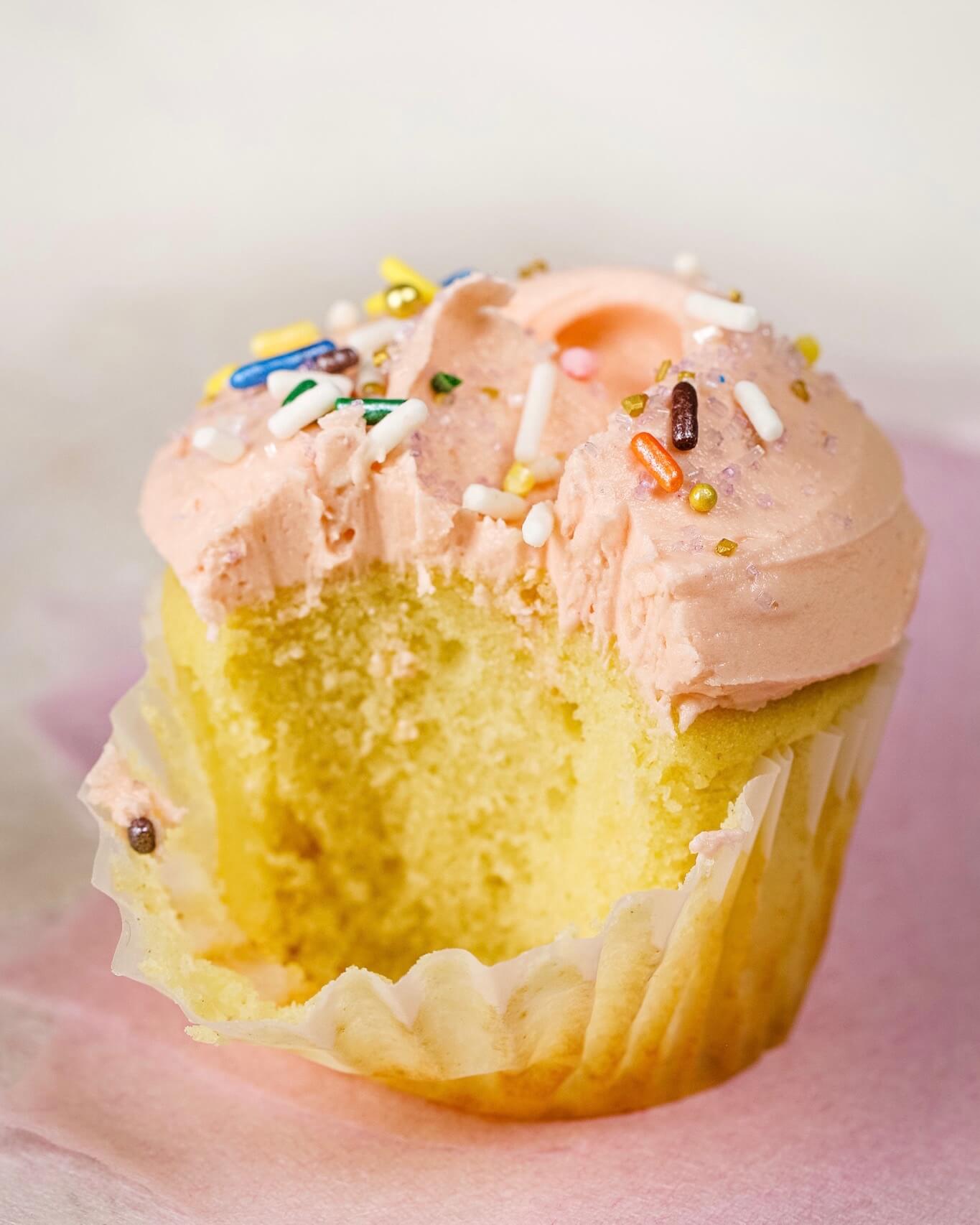 close up on vanilla cupcake with vanilla frosting. A bite has been taken out