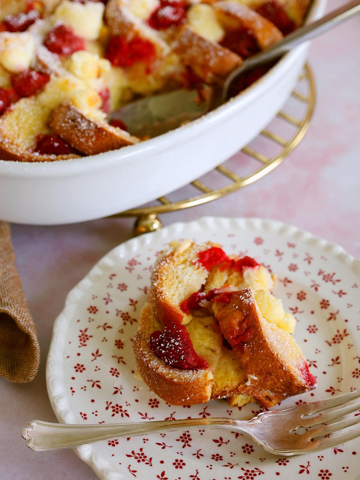A serving of raspberry bread pudding on a white plate.