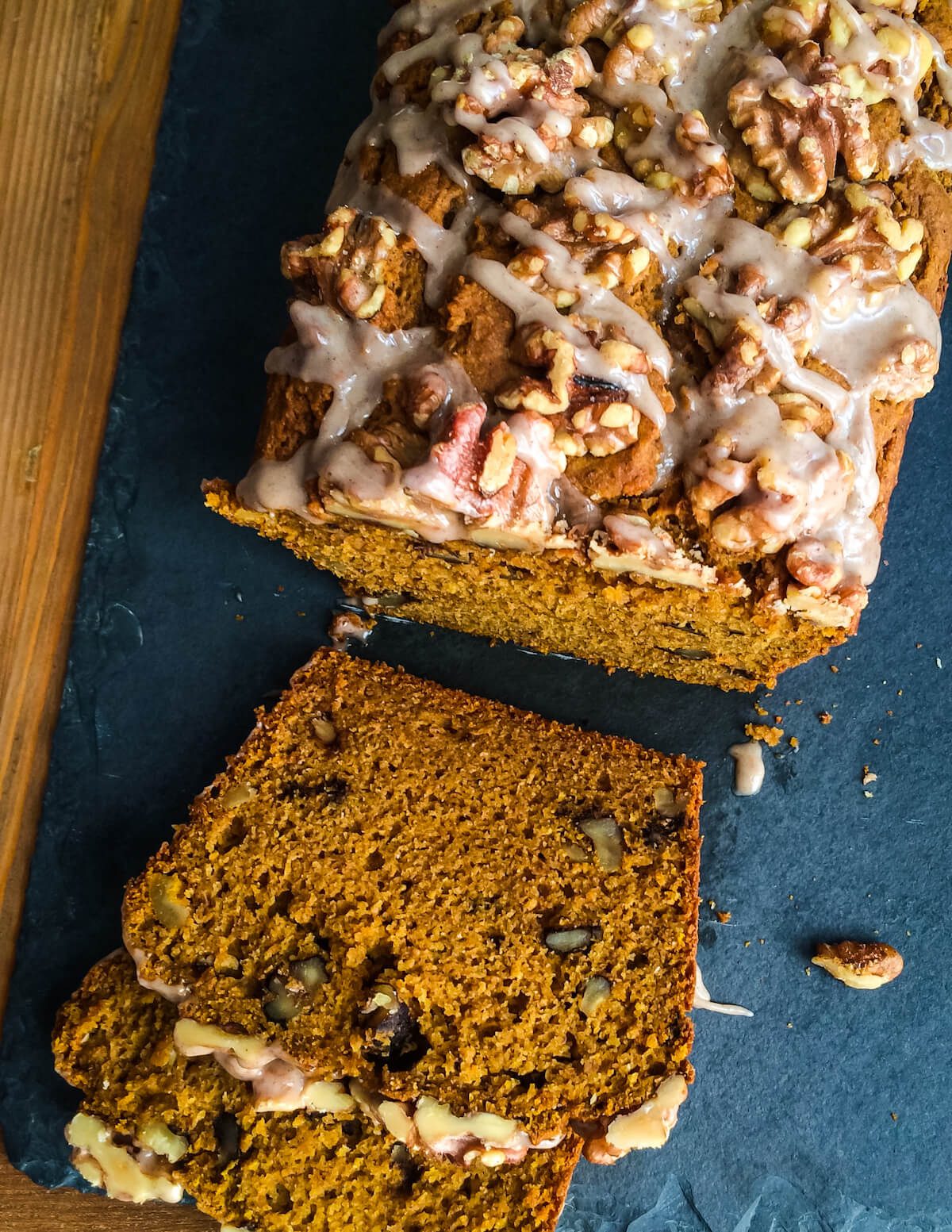 walnut pumpkin quick bread with icing on top sliced on a slate