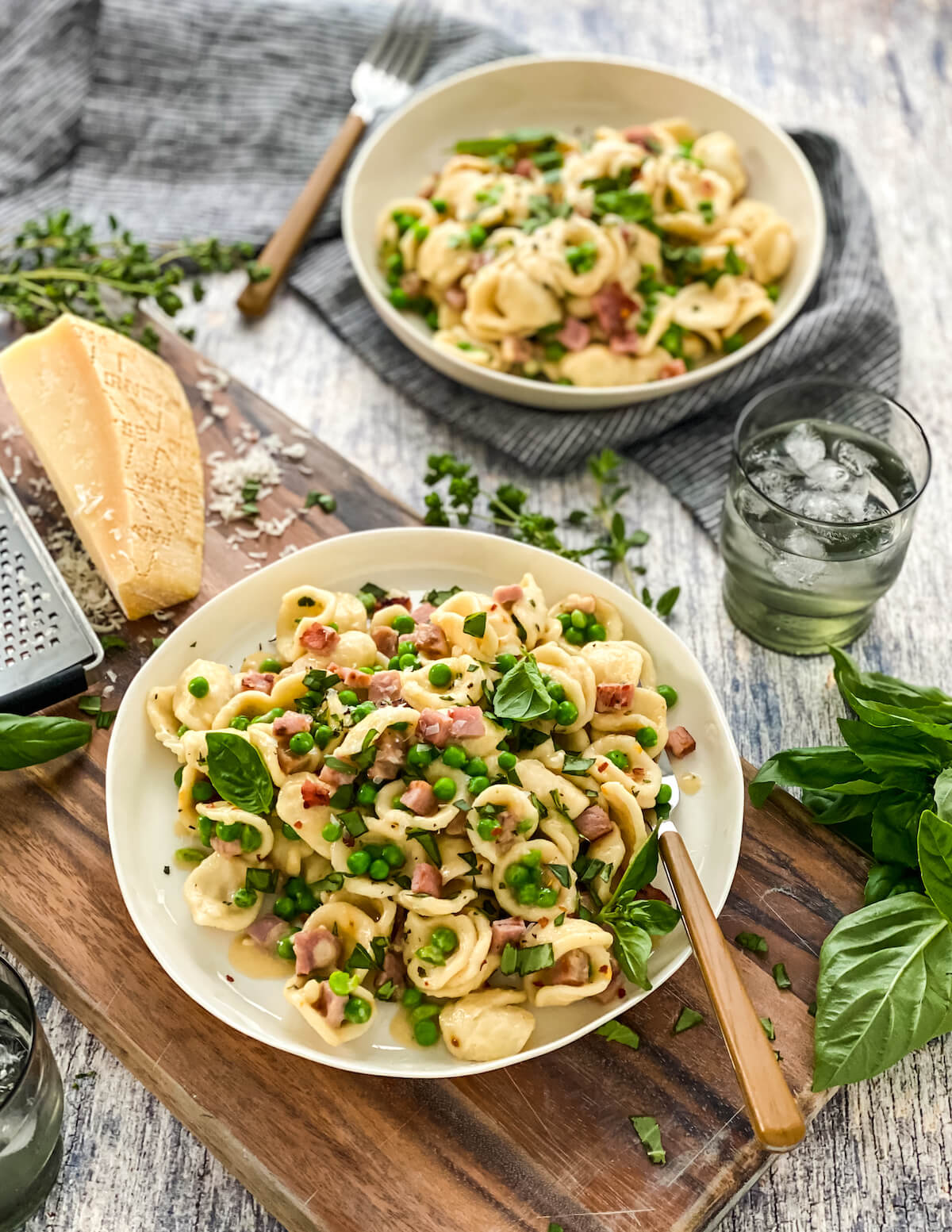 two bowls of pasta with ham and peas