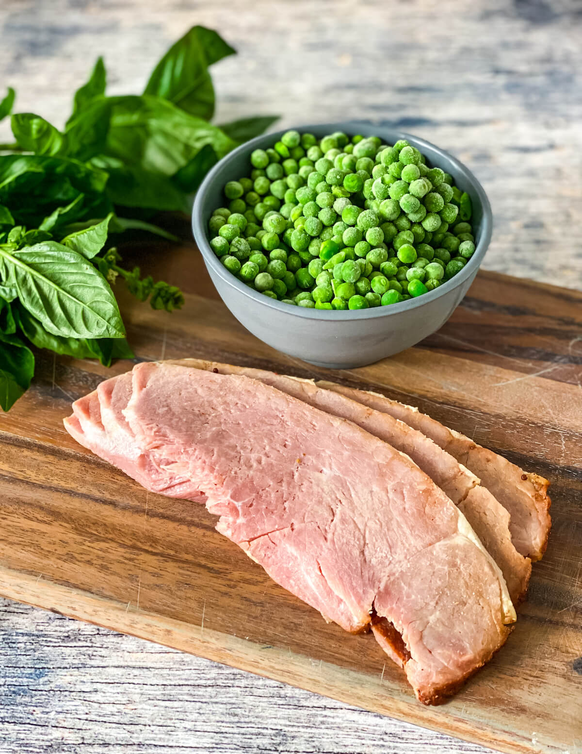 peas and ham with basil on cutting board
