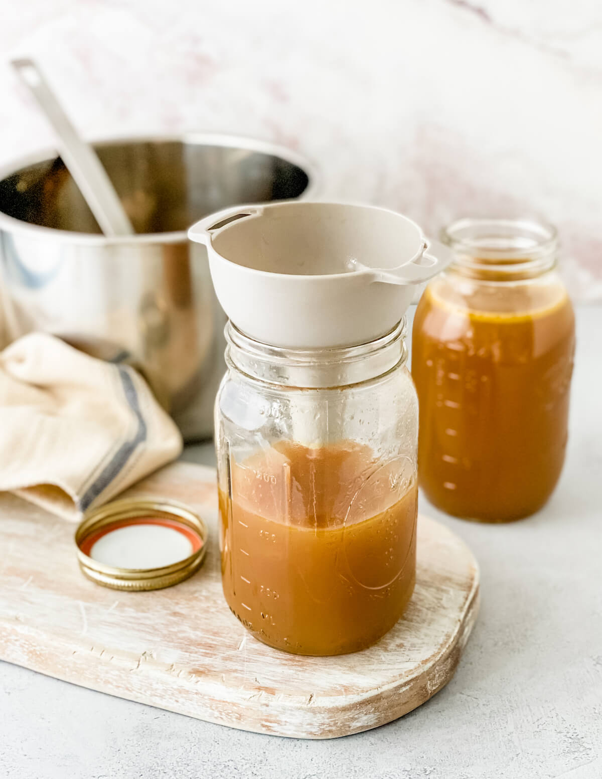 pouring turkey stock into a glass jar with a funnel