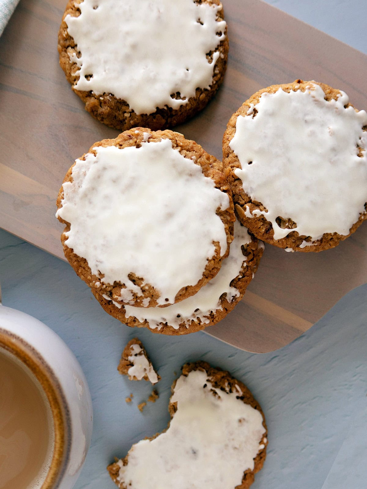 Several iced oatmeal cookies on a wooden cutting board.