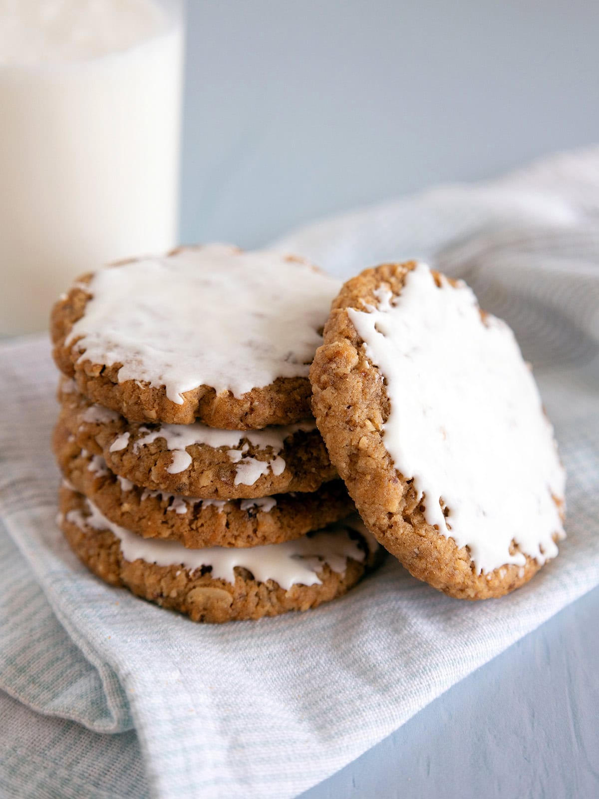 A stack of 3 oatmeal cookies with a 4th cookie leaning against the stack.