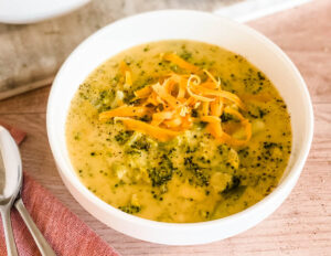 close up of yellow broccoli cheddar soup with bits of broccoli