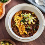Top view of a bowl of chili with toppers.