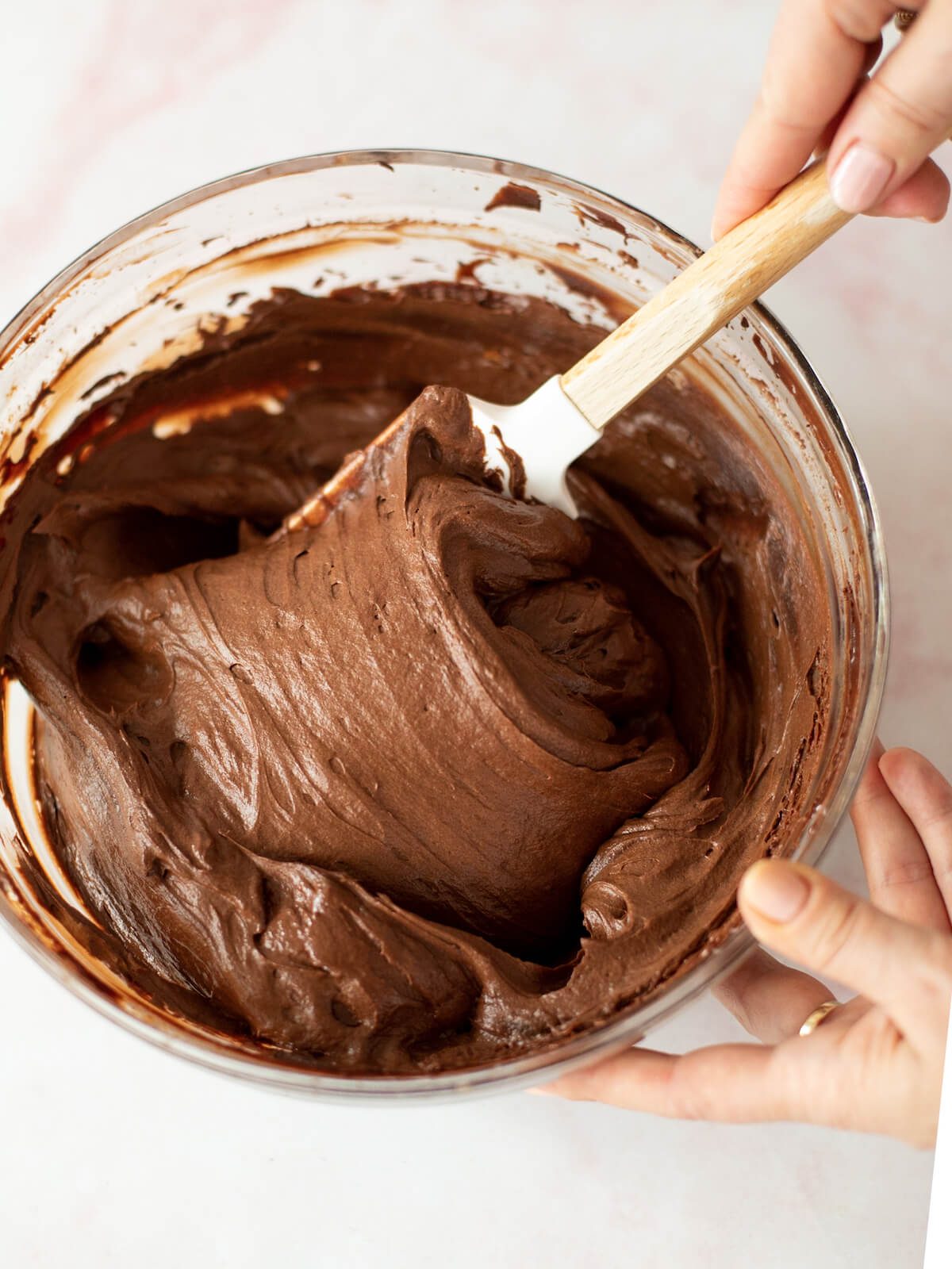 stirring chocolate frosting in glass bowl