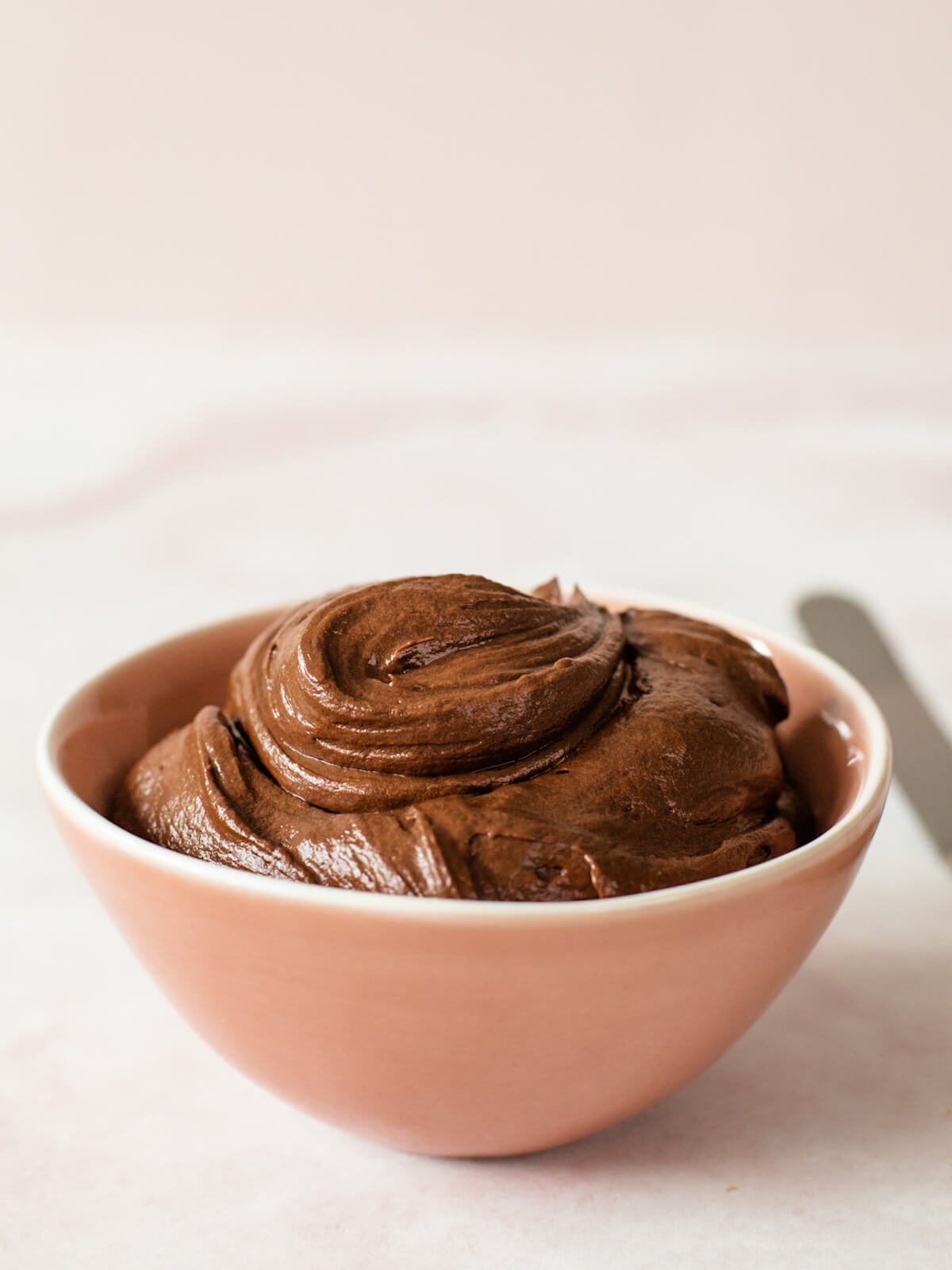 pink bowl of chocolate ganache frosting