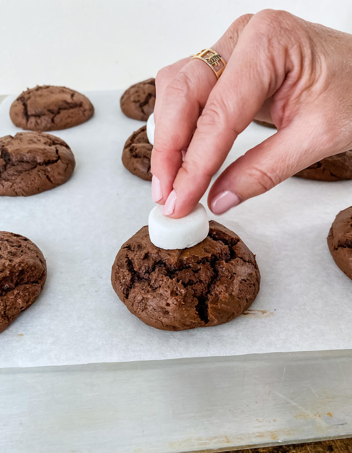 pressing marshmallow on top of warm cookies