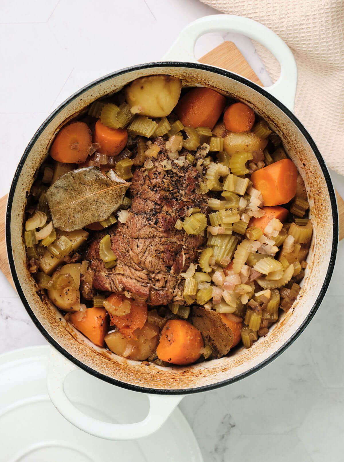 pot roast with vegetables in a white Dutch oven