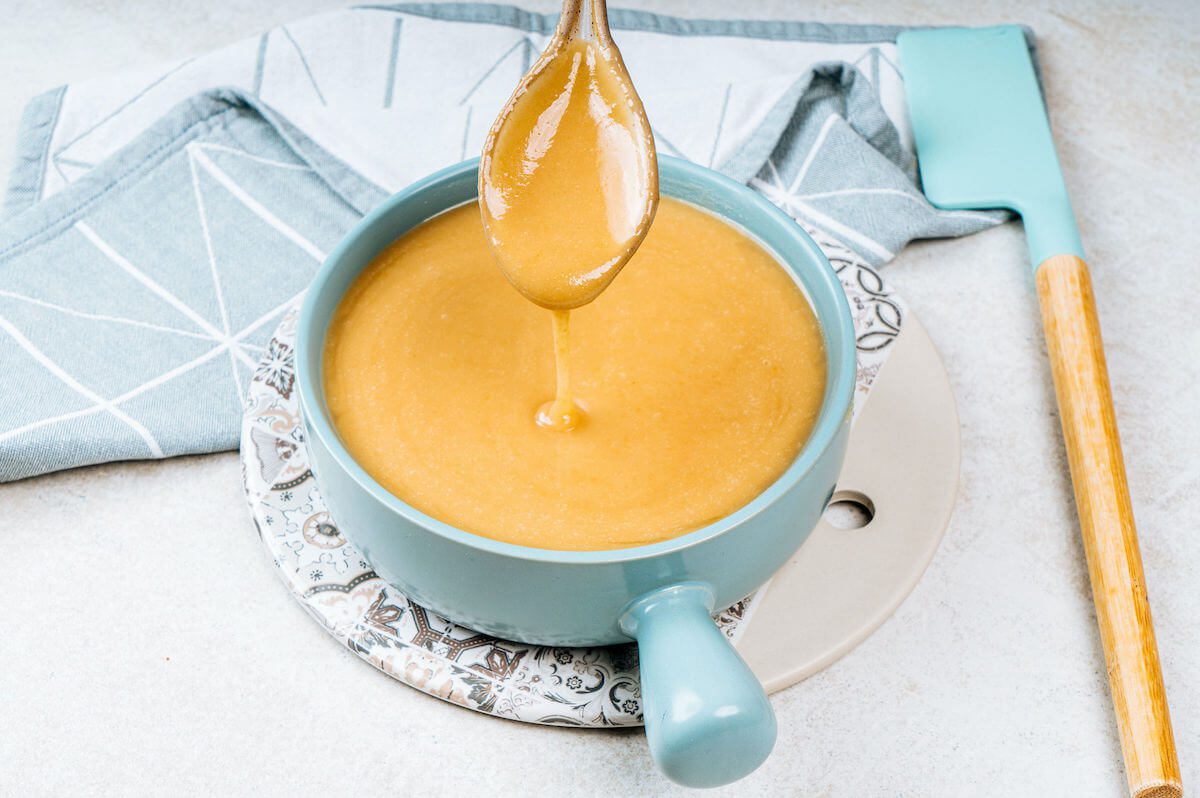 caramel icing dripping off a spoon into a bowl