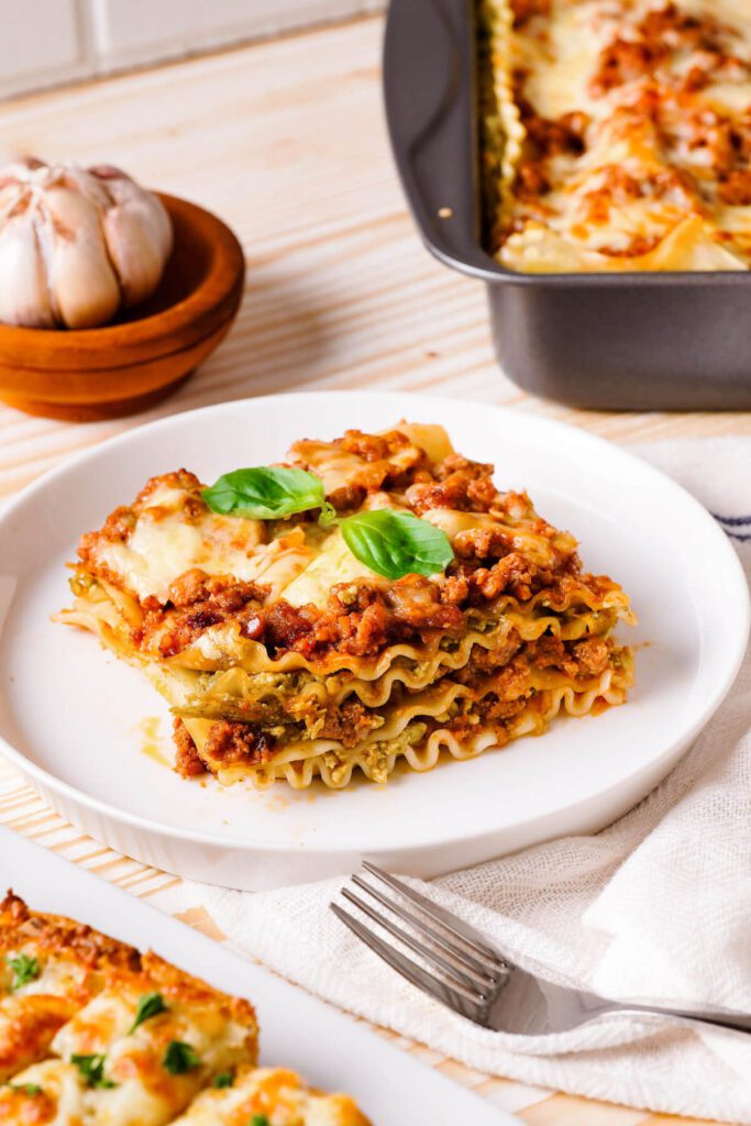 single serving of pesto lasagna on a plate with pan in background