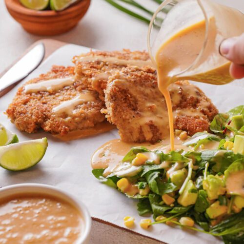 breaded pork cutlets with spicy dressing and salad on a plate