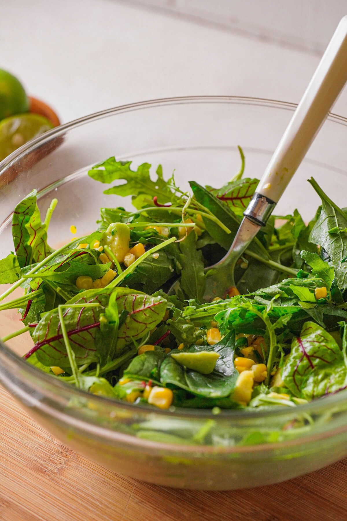 green salad with corn and avocado in a glass bowl