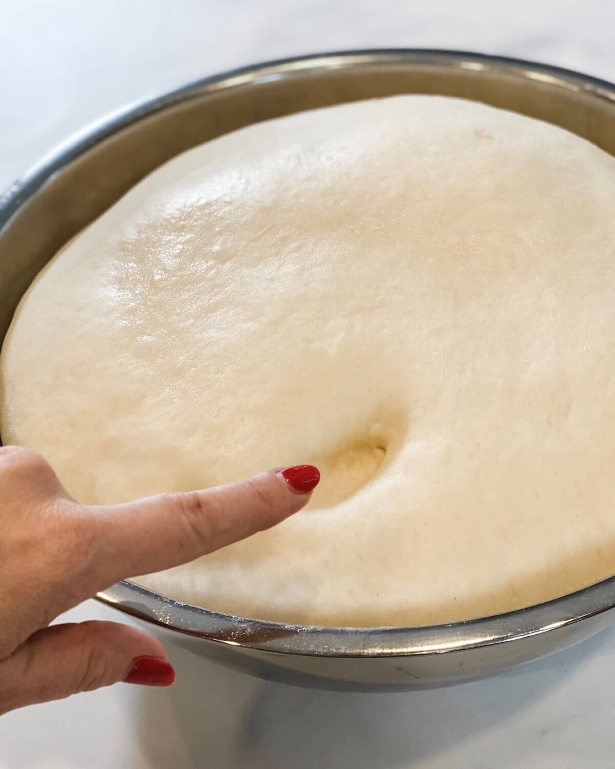 testing proved roll dough in a mixing bowl.