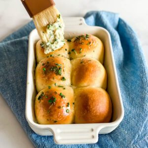 dinner rolls being brushed with herb butter