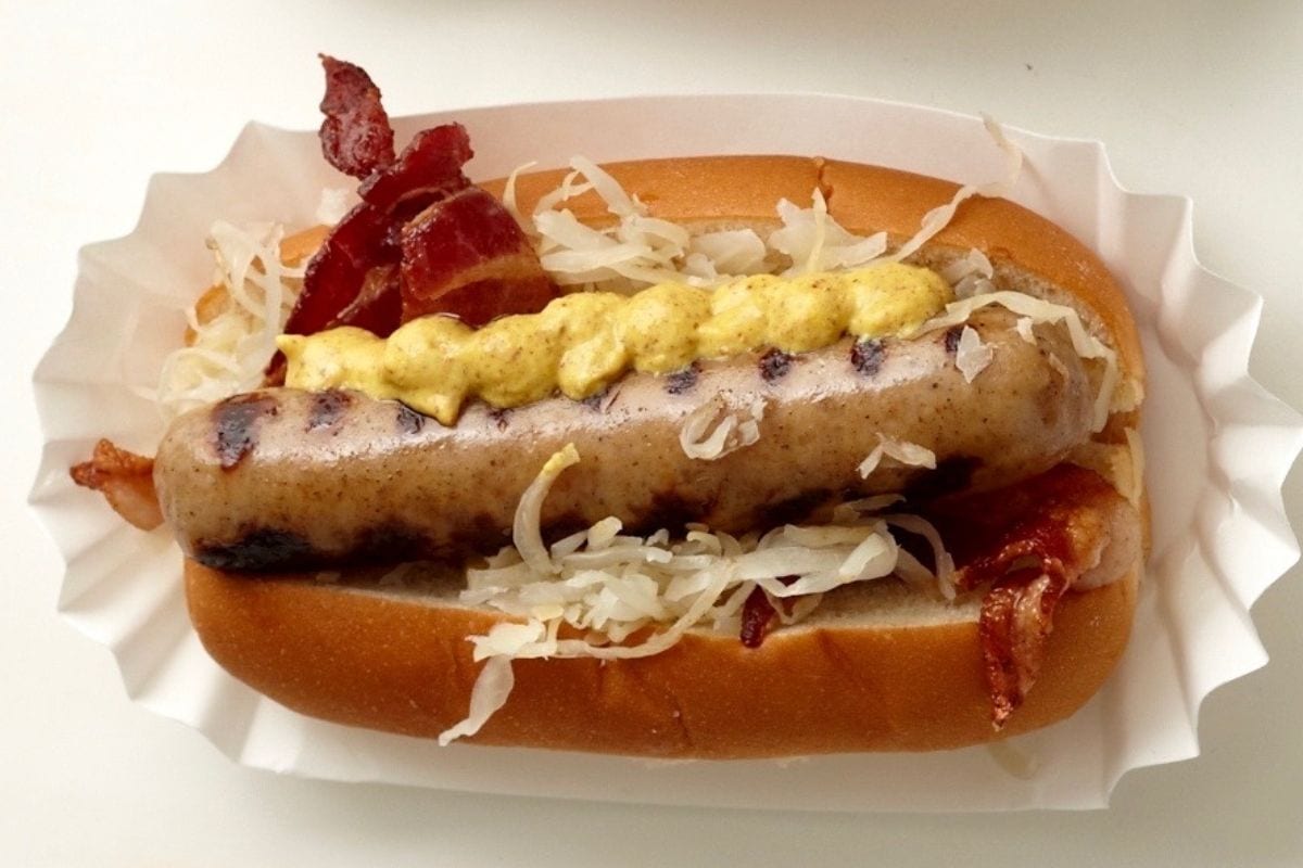 Close up of a beer brat with toppings.