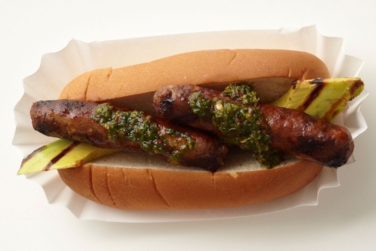 A wild game sausage in a bun with toppings.
