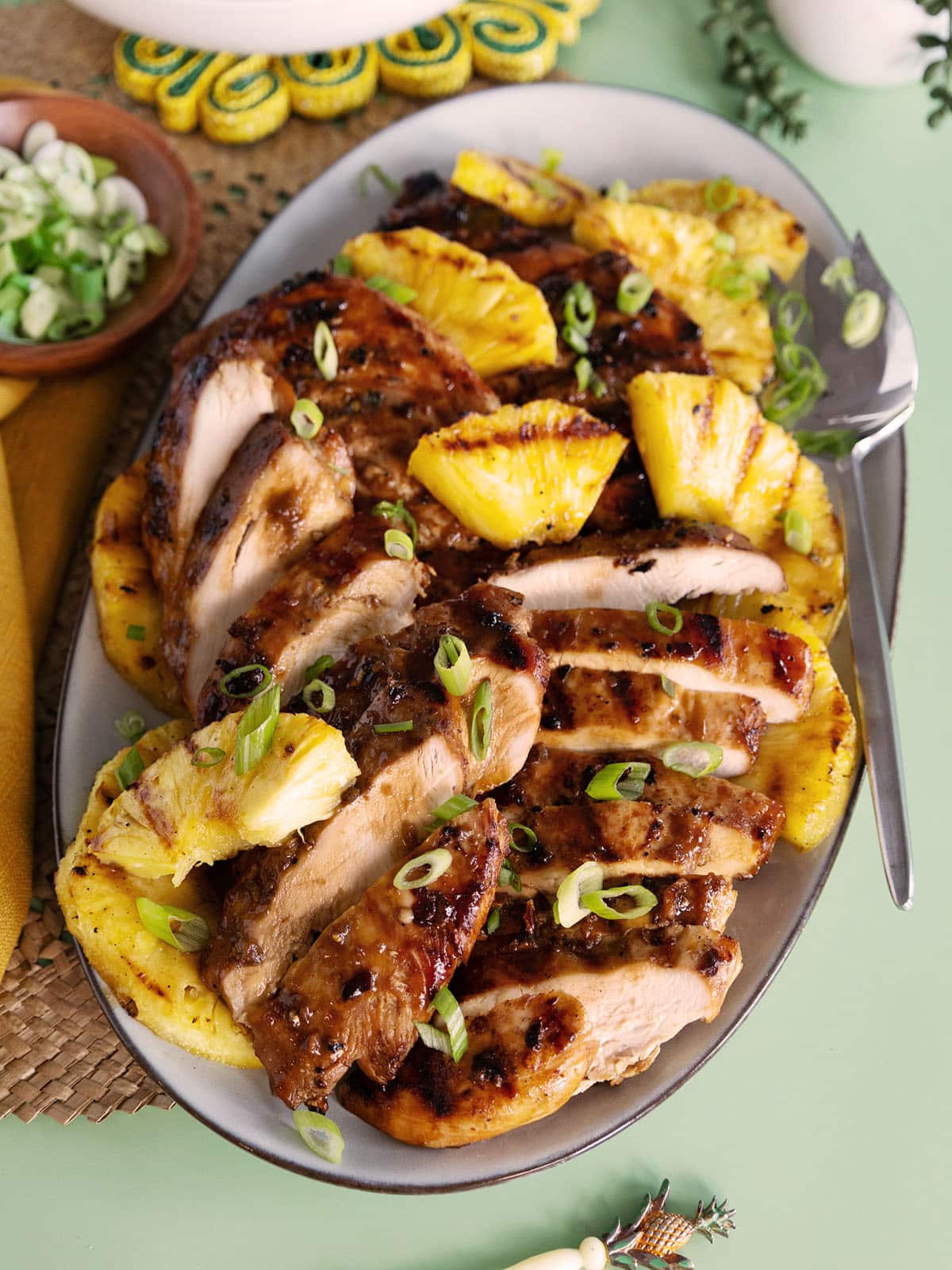 A platter of sliced grilled chicken and grilled pineapple. 