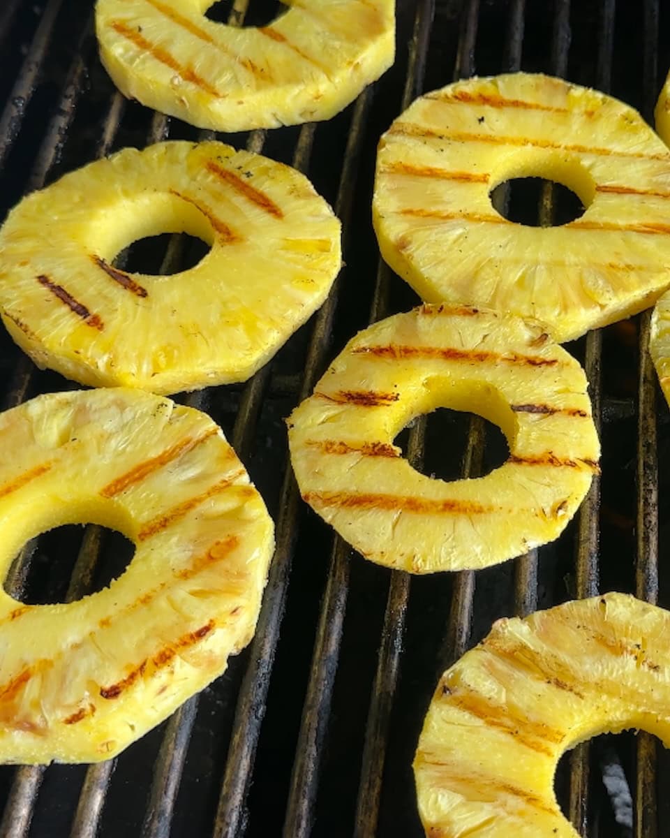Grilled pineapple rings on a hot grill.