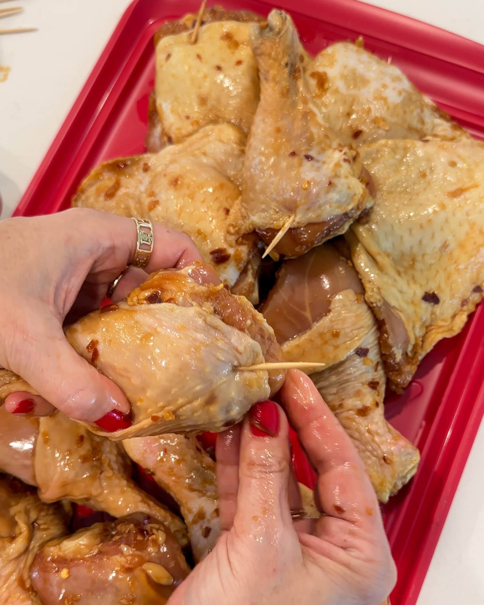 Toothpicks being inserted into chicken to secure the skin.