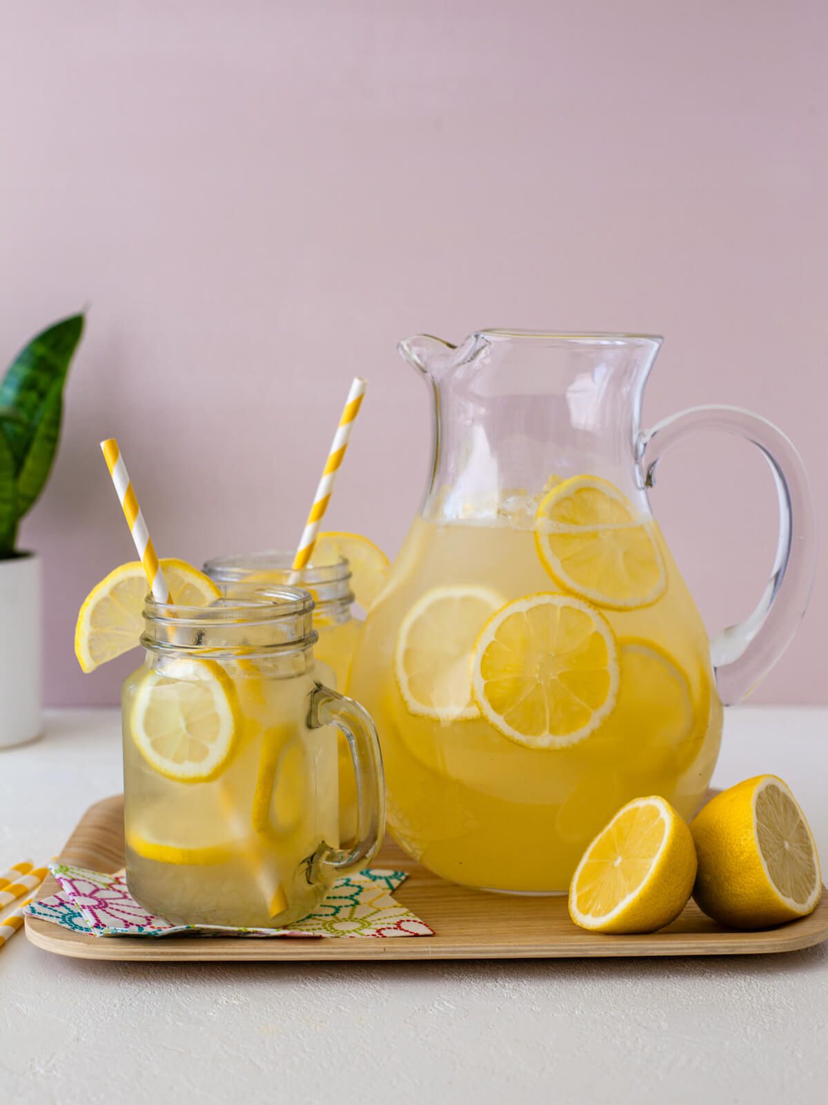 pitcher of homemade lemonade with clear mason jar mugs of lemonade