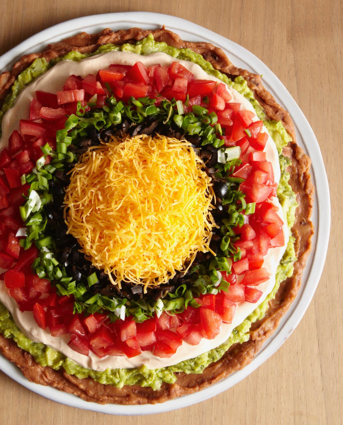 Close up of bullseye style 7 layer dip with cheese and beans and vegetables.